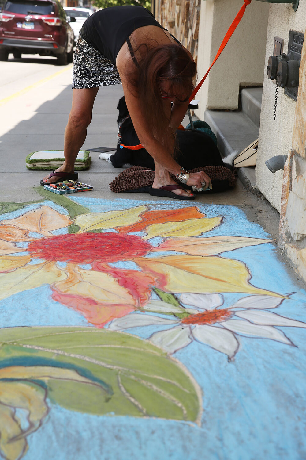 Vangie Hansen finishes the edges of her flowery sidewalk square